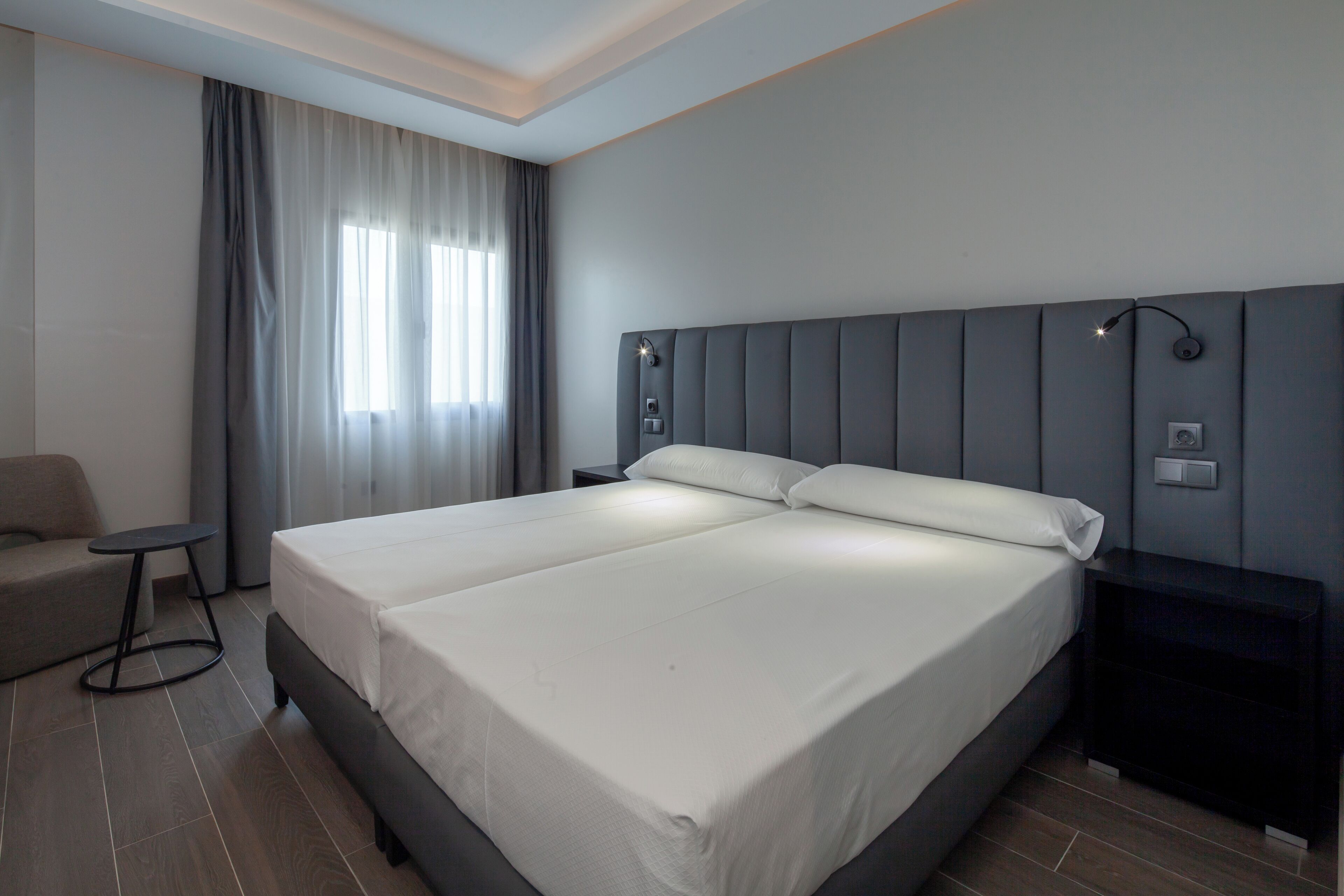 Una habitación de hotel moderna con una cama grande, un escritorio pequeño y una silla.