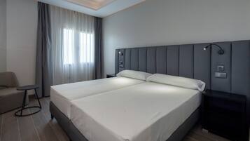 Una habitación de hotel moderna con una cama grande, un escritorio pequeño y una silla.
