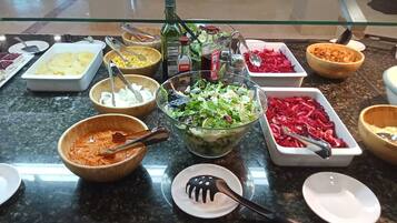 Uma mesa de buffet com diversos alimentos e acompanhamentos.