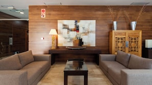 A modern lobby with a large abstract painting, a wooden cabinet with intricate designs, and a sleek coffee table. - Hotel Leflet Sanlúcar (Sanlucar la Mayor)