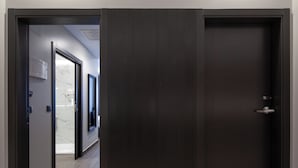 A modern hallway with a dark wooden door, a marble wall, and a ceiling-mounted air conditioning unit. - Hotel Leflet Sanlúcar (Sanlucar la Mayor)