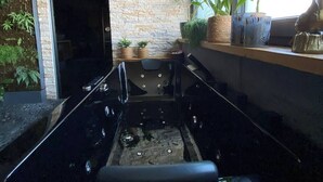 A modern kitchen with a black countertop, a built-in oven, and a window with plants and decorative items. - Emerald Suite with whirlpool, sauna and massage chair (Essen)