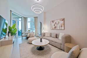 Una sala de estar moderna con una mesa de centro redonda, un sofá y un comedor con vistas a la ciudad.