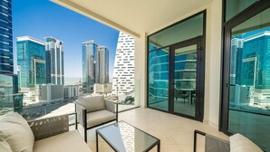 Un balcón moderno con una mesa de vidrio, sofá color beige y vistas a la ciudad.