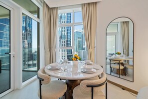 A modern dining room with a round table, chairs, and a large window with curtains.