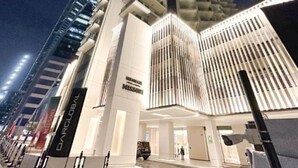 Un moderno edificio de gran altura con una entrada destacada y líneas verticales en la fachada.