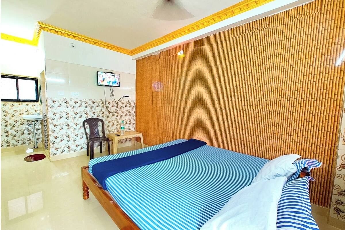 Un dormitorio con cama, televisor, silla y una mesita.