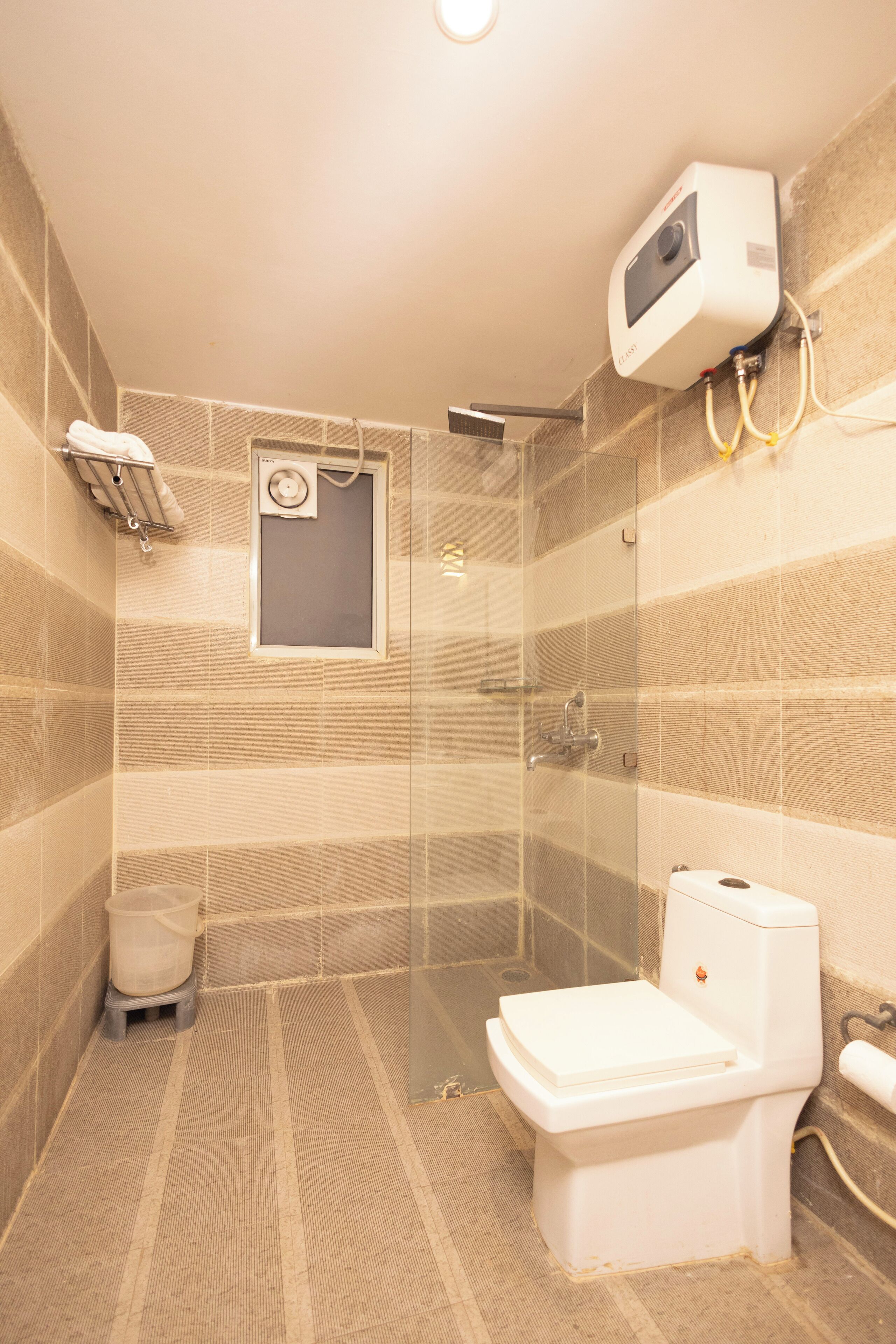 A bathroom with a shower, toilet, and a small window.