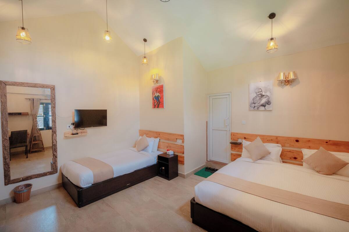 A hotel room with two beds, a TV, a mirror, artwork, and a wooden headboard.