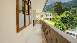 A balcony with a view of a house and lush greenery. - Hotel O Villa Beringin Puncak (Cisarua)