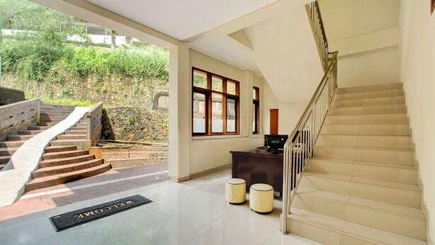 A hotel lobby with a staircase, a reception desk, and a welcome mat. - Hotel O Villa Beringin Puncak (Cisarua)