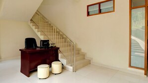 A staircase with a wooden handrail and beige steps, leading to a landing with a desk and two cylindrical lamps. - Hotel O Villa Beringin Puncak (Cisarua)