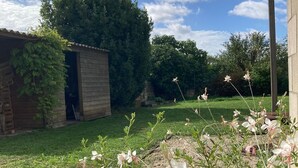 A garden with a wooden shed, a grassy lawn, and flowering plants. - L'Annexe - 100m² family home near Futuroscope (Lavoux)