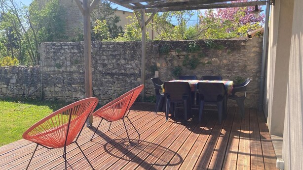 An outdoor wooden deck with a pergola, stone wall, and a table with chairs. - L'Annexe - 100m² family home near Futuroscope (Lavoux)