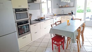 A kitchen with a dining area, featuring a table, chairs, and a red chair. - L'Annexe - 100m² family home near Futuroscope (Lavoux)