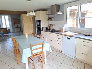 A kitchen with a dining table, chairs, a dishwasher, a stove, and a window. - L'Annexe - 100m² family home near Futuroscope (Lavoux)