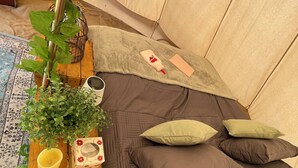 Et hyggeligt og velorganiseret soveområde med en seng, puder, et lille bord med lampe og diverse planter.