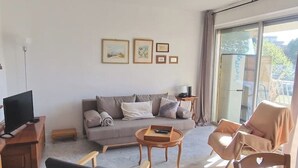 A living room with a sofa, two armchairs, a coffee table, and a TV on a wooden stand.