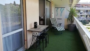A balcony with a small table, a chair, and a potted plant.