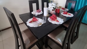 Een eettafel gedekt met witte borden, rode servetten en gouden bestek.