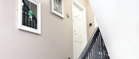 A staircase with a handrail, a door, and two framed pictures on the wall.
