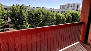 A balcony with a red metal railing overlooking a row of trees and buildings. - Large, modern, air-conditioned T4 (Montpellier)