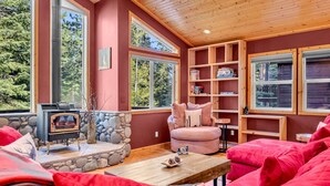 A cozy room with a stone fireplace, a sofa, and a bookshelf. - Modern Retreat in Truckee with A/C & Game Room (Truckee)