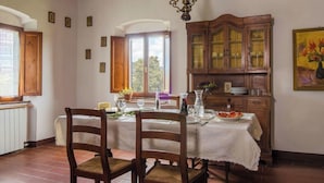 A dining room with a wooden table set for two, a cabinet with glass doors, and a painting on the wall. - Comfort two-room apartment with a view (Toscana)