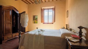 A bedroom with a large bed, wooden wardrobe, and a window with a view. - Comfort two-room apartment with a view (Toscana)