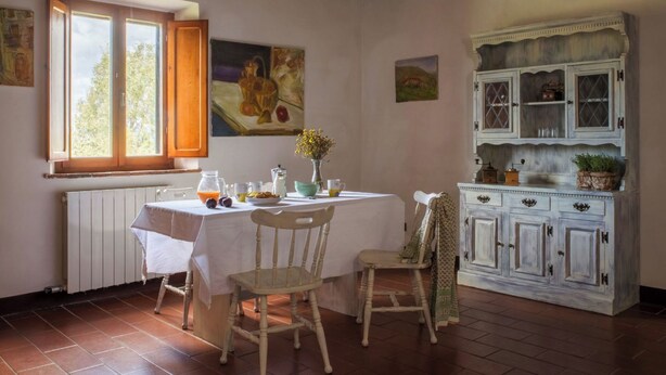 A dining area with a table set for breakfast, a radiator, and a cabinet with glass doors. - Comfort two-room apartment with a view (Toscana)