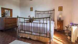 A bedroom with a four-poster bed, wooden dresser, and a small table with flowers. - Comfort two-room apartment with a view (Toscana)