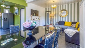 A modern living room with a glass dining table, a sofa with colorful cushions, and a striped wall. - Gorgeous home in Royan (Royan)