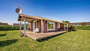 A single-story house with a covered porch, a satellite dish, and a lawn.