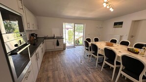 Een moderne keuken met een eetgedeelte, houten vloeren en een uitzicht door de glazen deur.