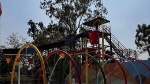 Un espace de jeux aquatiques avec de nombreux jets d’eau colorés et, en arrière-plan, une structure de jeux pour enfants.
