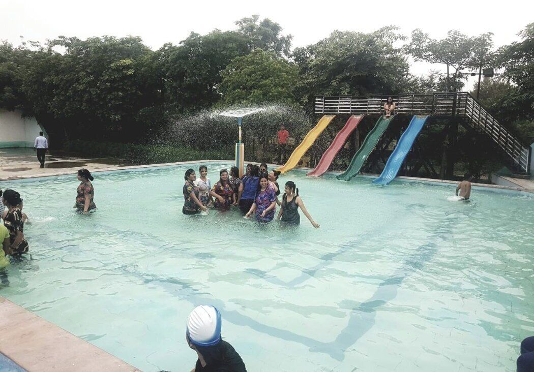 A swimming pool with multiple slides and a group of people in the water.