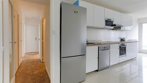 Een moderne keuken met witte kasten, een roestvrijstalen koelkast, een magnetron en een vaatwasser.
