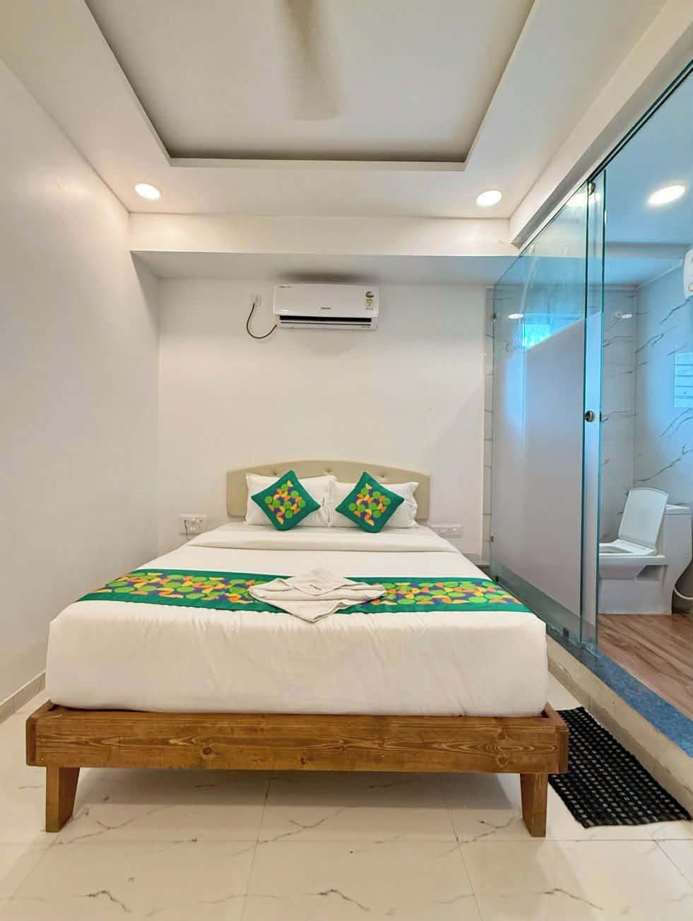 A bedroom with a wooden bed, white bedding, and a green patterned throw.