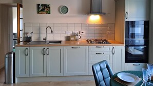 A modern kitchen with a central island, a gas stove, a sink, and a built-in oven. - Quiet, rural hideaway in traditional old Schoolhouse, right on the edge of loch. (Isle of Lewis)
