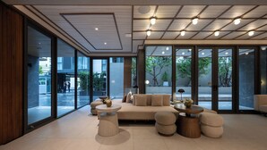 A modern interior with a sofa, round tables, and a view of the outside. - The Moment (Bangkok)