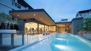 A modern hotel with a swimming pool, outdoor seating, and a covered area with glass walls. - The Moment (Bangkok)