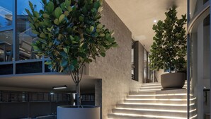 A modern building exterior with a staircase leading to the entrance, surrounded by potted plants and illuminated by under-stair lighting. - The Moment (Bangkok)