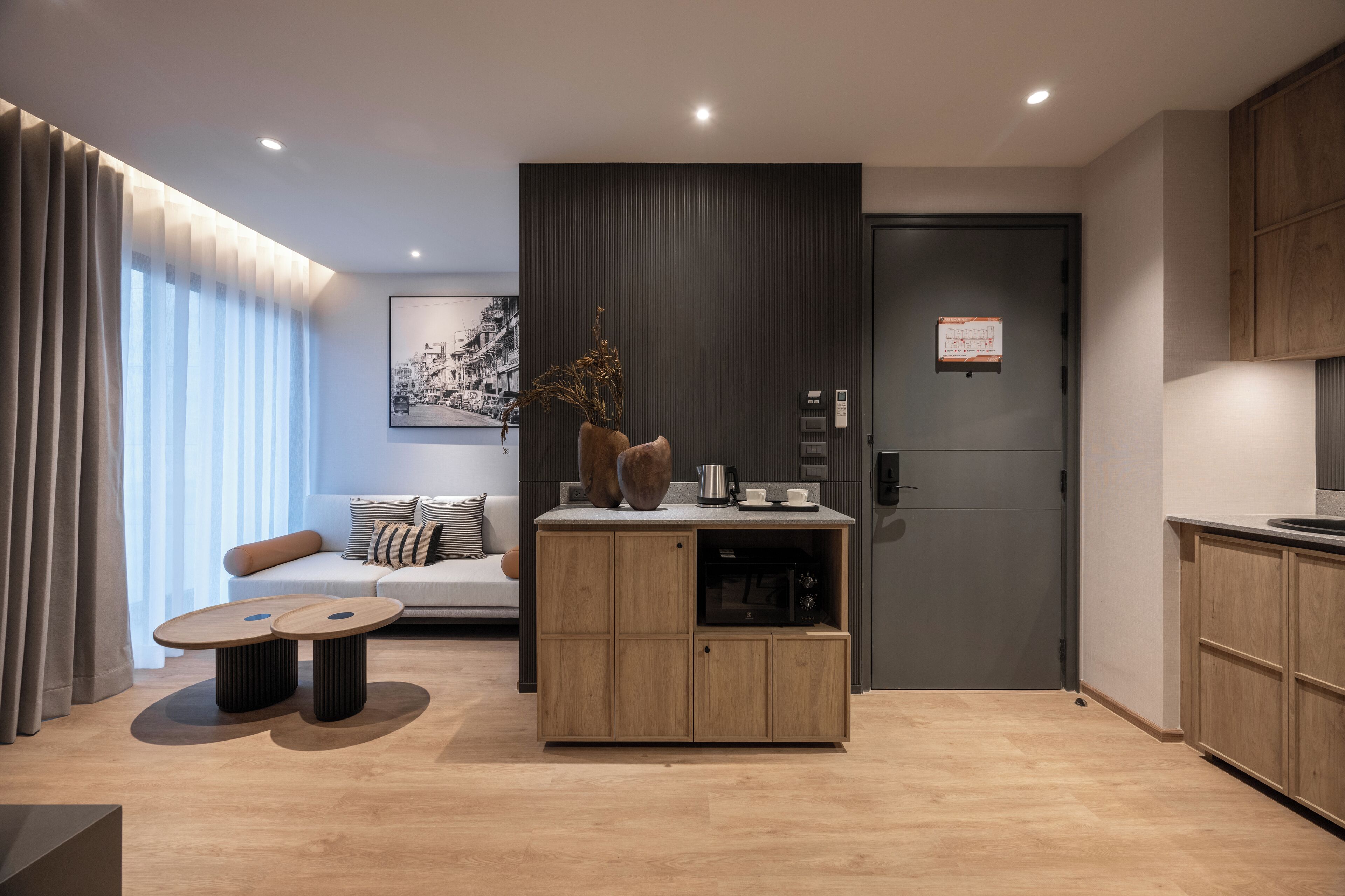 A modern living room with a sofa, coffee table, and a built-in kitchen area with cabinets and a microwave.