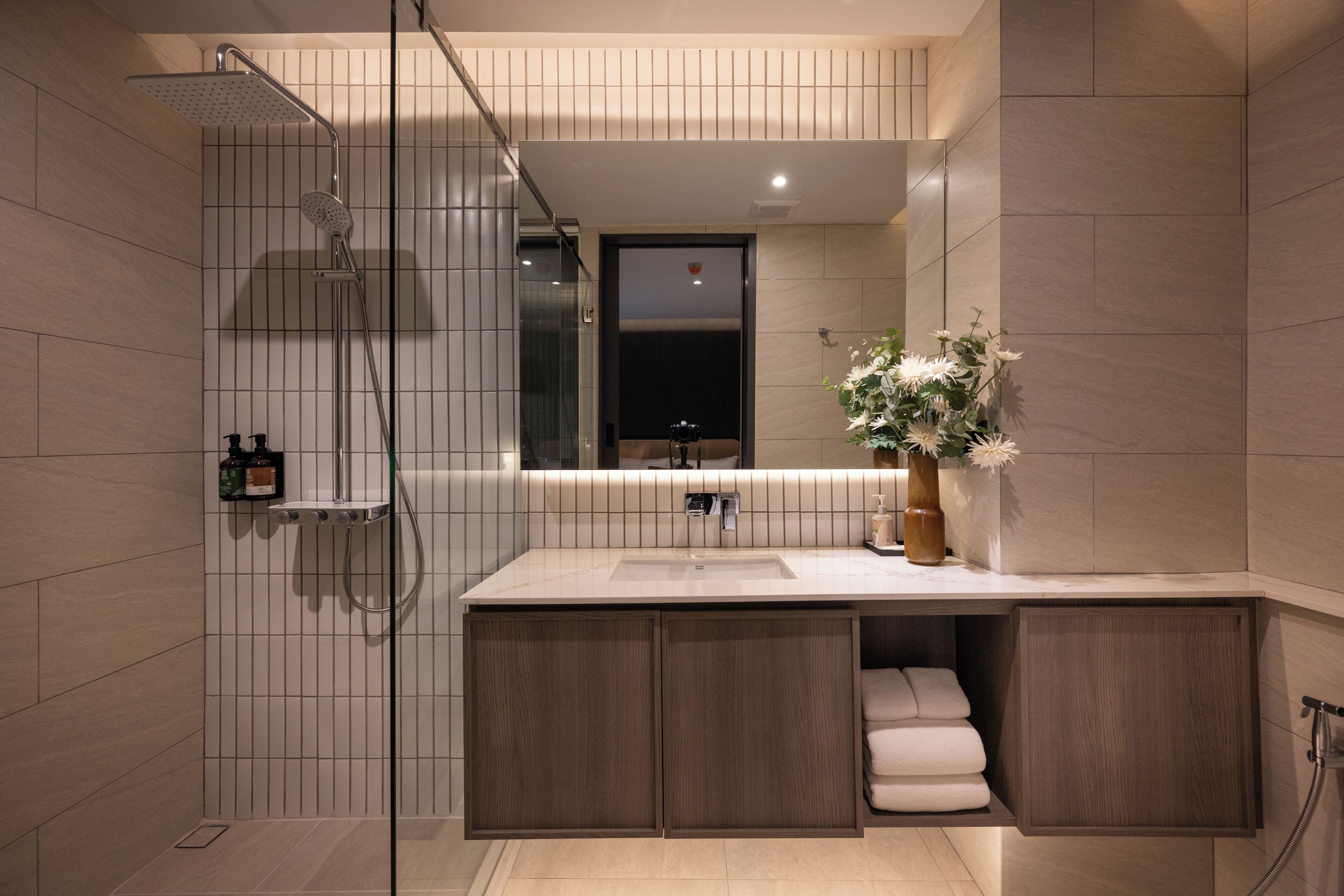 Un baño moderno con ducha, lavamanos y espejo.