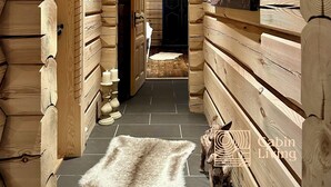 A wooden cabin interior with a hallway leading to a door, a mounted picture, and a small rug on the floor. - Stylish log cabin in Hafjell w/view & sauna (Øyer kommune)