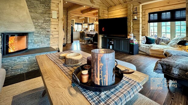 A cozy cabin interior with a stone fireplace, a large TV, and a comfortable seating area. - Stylish log cabin in Hafjell w/view & sauna (Øyer kommune)