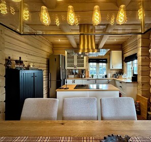 A modern kitchen with wooden walls, a central island, and pendant lighting.