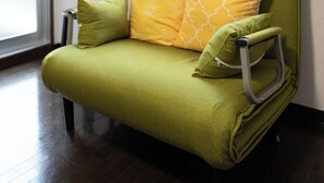 Un sofá verde con un reposacabezas, dos almohadas y un pomo metálico.