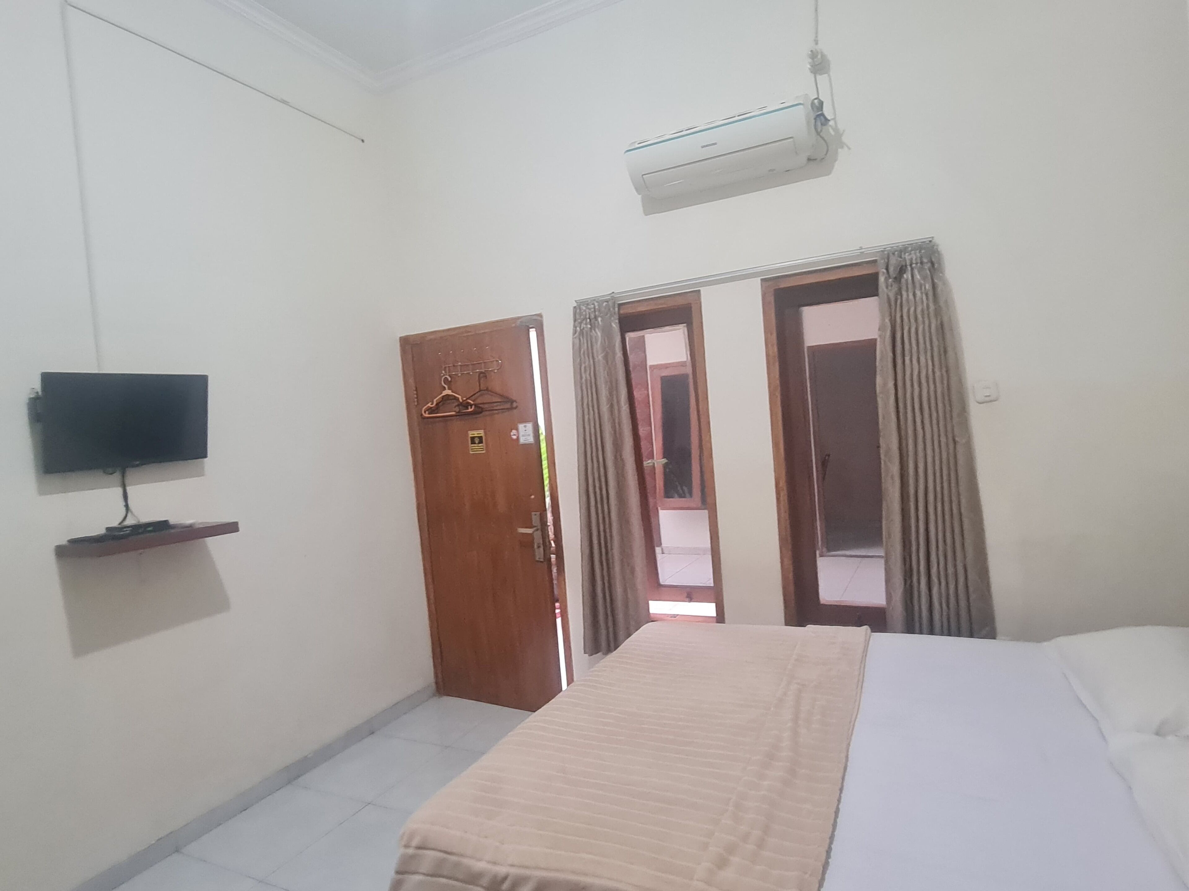 Une chambre d’hôtel équipée d’un lit, d’un téléviseur fixé au mur, d’une porte et d’un appareil de climatisation.