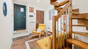 A modern interior with a wooden staircase, a yellow rocking chair, and a black door.